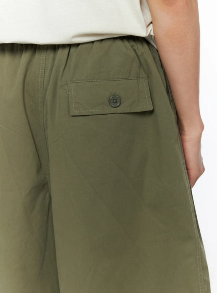 Men's Bermuda Shorts (Dark Green) IL514 Dark green close-up detail of back button flap pocket with contrast stitching and elastic waistband on model