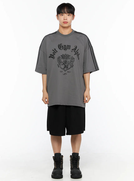 Men's Bermuda Sweat Shorts (Black) IL514 Black straight-on front shot on male model with grey graphic tee and black boots, hands at sides showing relaxed wide-leg silhouette