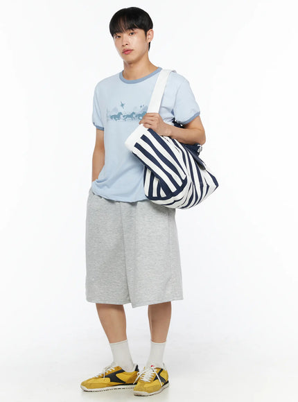 Men's Bermuda Sweat Shorts (Gray) IL514 Gray full-body front shot on male model styled with light blue graphic tee and striped tote bag over shoulder