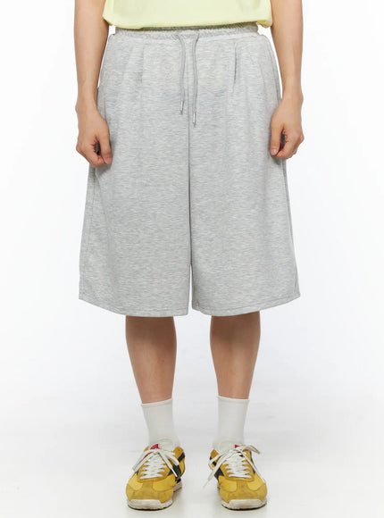 LEWKIN Men's Bermuda Sweat Shorts (Gray) IL514 Gray front view on model wearing yellow sneakers, heather gray fleece fabric with drawstring waist