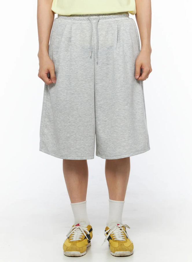 LEWKIN Men's Bermuda Sweat Shorts (Gray) IL514 Gray front view on model wearing yellow sneakers, heather gray fleece fabric with drawstring waist