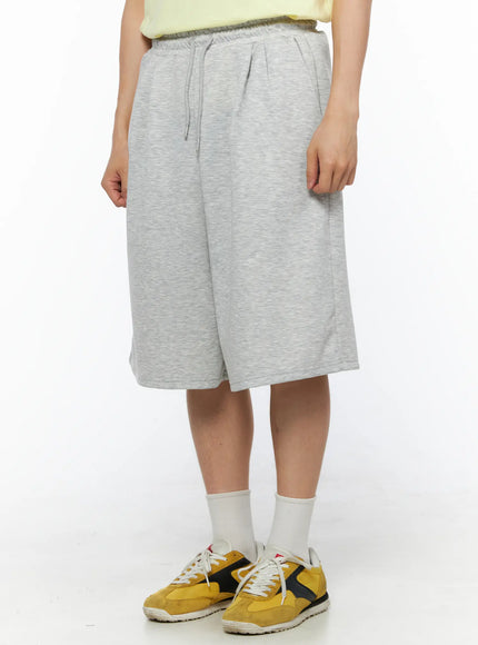 Men's Bermuda Sweat Shorts (Gray) IL514 Gray angled front view on model showing side silhouette, drawstring waistband and wide-leg cut