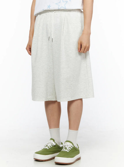 Men's Bermuda Sweat Shorts (Light Gray) IL514 Light gray side-angle close-up on model highlighting pleated waist drawstring detail and relaxed silhouette with green sneakers