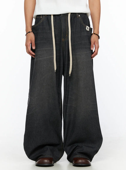 LEWKIN Men's Bryan Drawstring Baggy Jeans IL520 Black size M/L front crop shot on model wearing white top, cream drawstring, faded black denim
