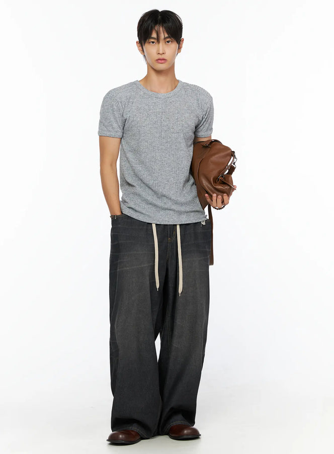 Men's Bryan Drawstring Baggy Jeans IL520 Black full-body front on male model styled with grey knit tee and brown leather bag, cream drawstring, baggy fit