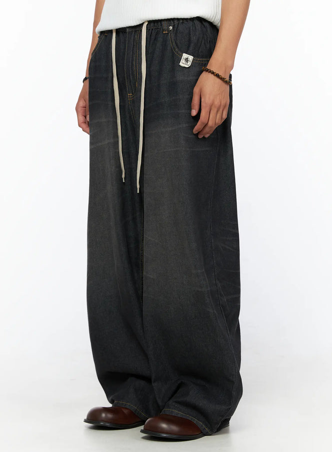 Men's Bryan Drawstring Baggy Jeans IL520 Black side view on model showing cream drawstring, brand patch label, yellow topstitching, ultra-wide leg denim