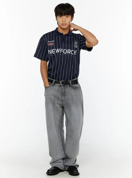 Men's Bryce Distressed Wide-Leg Jeans IL509 Light gray front full-length shot on male model in navy NEWFORCE polo, hand raised to neck, relaxed pose