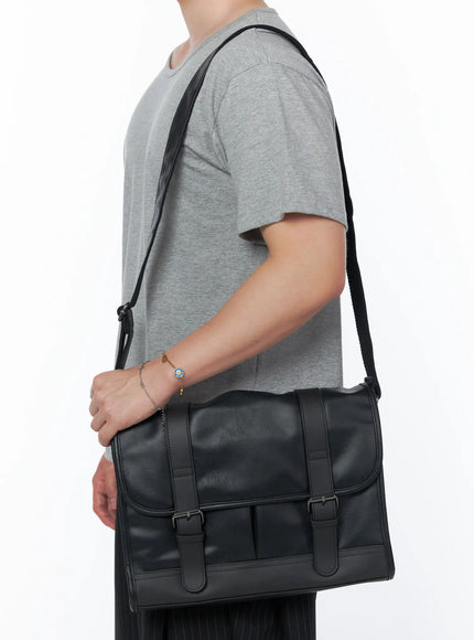 Men's Buckle Crossbody Bag IU523 Black side shot on male model wearing gray tee and pinstripe trousers carrying bag on shoulder