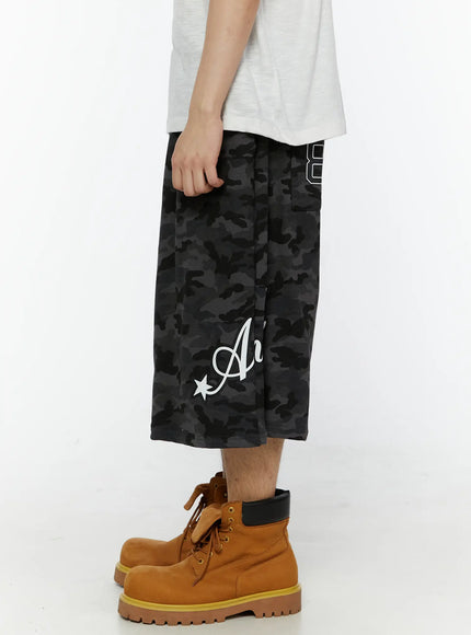 Men's Camo Graphic Shorts (Dark Gray) IL509 Dark gray side angle view on model highlighting oversized fit, camo texture, and partial 89 numeral graphic at back waist