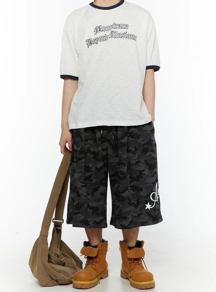 Men's Camo Graphic Shorts (Dark Gray) IL509 Dark gray full-body front styling on model with graphic tee, crossbody bag, and boots, loose fit camo shorts