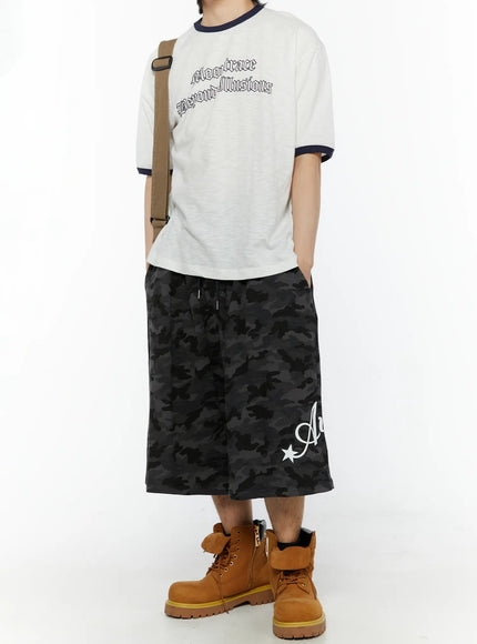 Men's Camo Graphic Shorts (Dark Gray) IL509 Dark gray full-body outfit shot on model with graphic ringer tee, crossbody bag, boots, front-facing stance