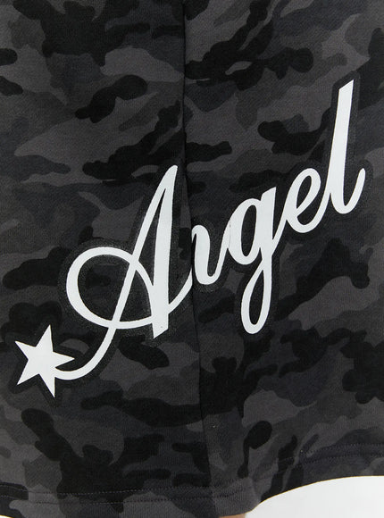 Men's Camo Graphic Shorts (Dark Gray) IL509 Dark gray close-up detail of white Angel cursive script print and star graphic on lower front hem, dark camo cotton fabric