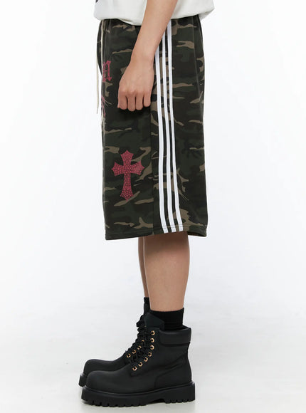 Men's Camo Graphic Sweat Shorts (Dark Green) IL514 Dark green side view on model showing white triple stripe detail and pink crackle cross graphic