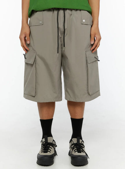 LEWKIN Men's Cargo Bermuda Shorts (Gray) IL509 Gray cropped front view on model wearing green top and sneakers, drawstring waist and dual cargo pockets