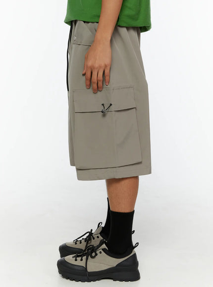 Men's Cargo Bermuda Shorts (Gray) IL509 Gray left side view on model highlighting oversized cargo pocket with metal toggle closure and nylon fabric