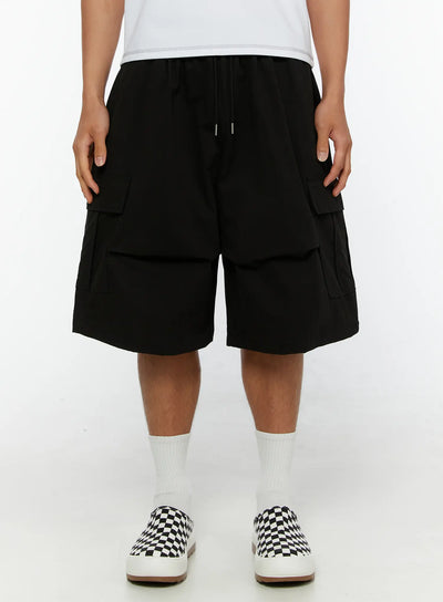 LEWKIN Men's Cargo Bermuda Shorts IL513 Black front view on male model wearing white tee and checkered slip-on sneakers, drawstring waist, double cargo pockets