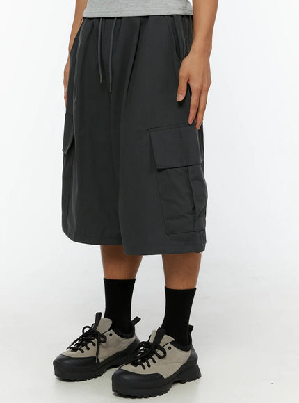 Men's Cargo Jorts IL510 Dark gray side close-up on male model left leg highlighting large cargo pocket and partial CHANGE RULE letter print