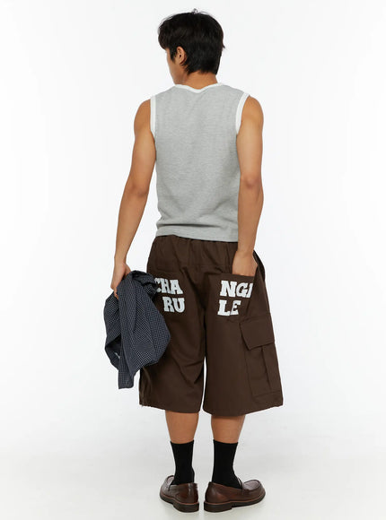 Men's Cargo Pocket Jorts IL510 Dark brown full back view on male model holding plaid shirt at side showing CHANGE RULE graphic print on rear pockets and wide-leg cut