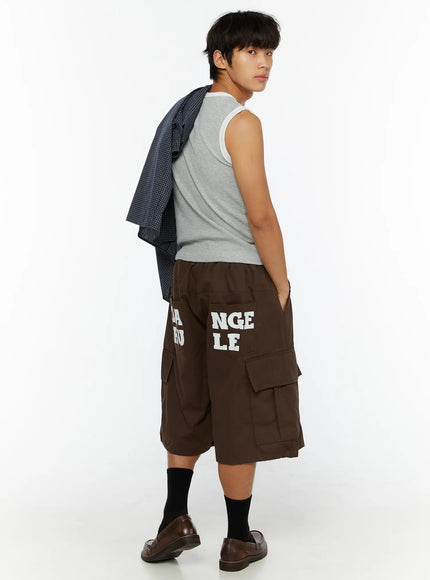 Men's Cargo Pocket Jorts IL510 Dark brown three-quarter back view on male model glancing over shoulder styled with gray sleeveless top and plaid shirt over shoulder