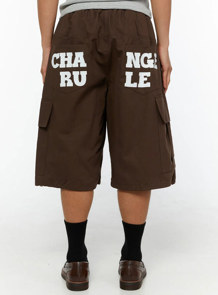 Men's Cargo Pocket Jorts IL510 Dark brown back close-up on model showing full white CHANGE RULE graphic print across rear pockets with elastic waistband and cargo pockets