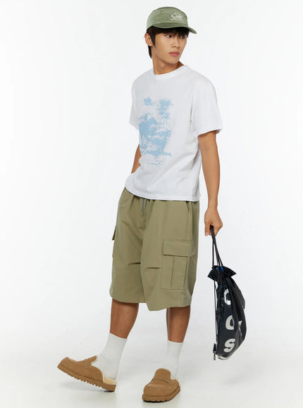 Men's Casual Graphic Print T-Shirt IL513 White full-length side-angle walking shot on male model with green cap and drawstring bag showing relaxed street style silhouette