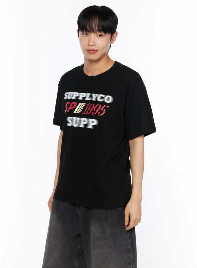 Men's Casual Graphic Tee IL514 Black angled close-up front shot on male model showing SUPPLYCO SP1995 SUPP graphic print detail