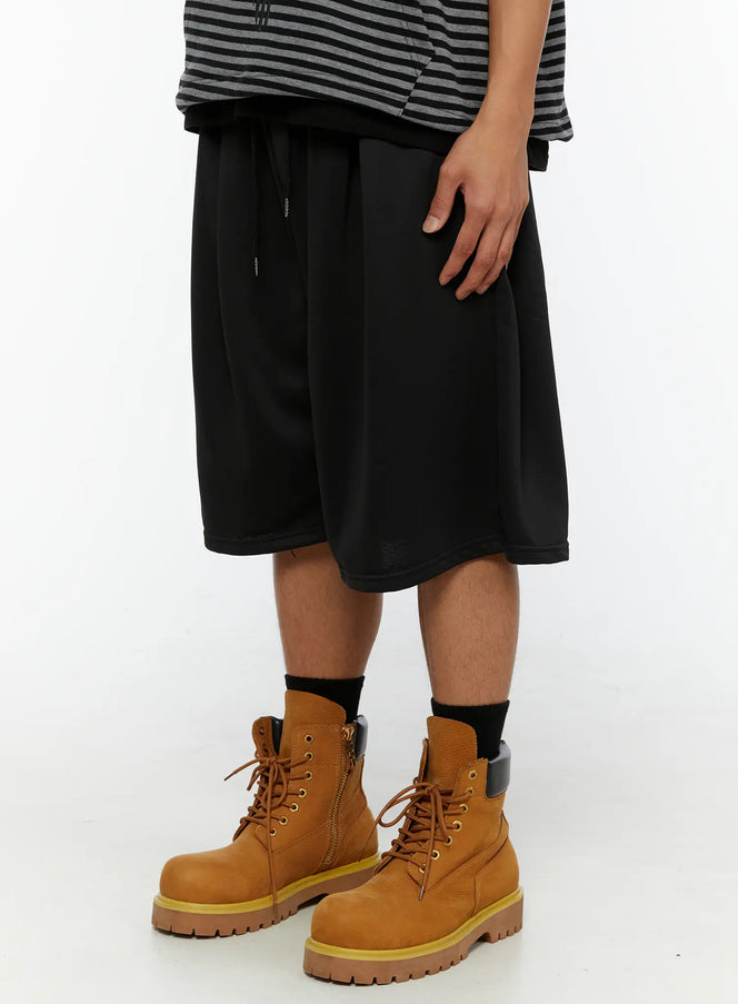 Men's Casual Jorts IL510 Black side close-up on model showing wide flared leg hem, smooth fabric texture, and tan lace-up boots styling