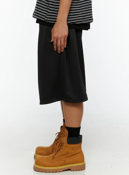 Men's Casual Jorts IL510 Black side shot on model showing drop-crotch silhouette, wide leg drape, and smooth matte fabric detail