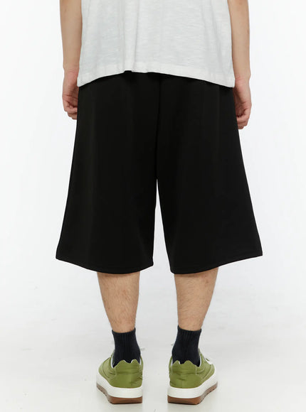 Men's Casual Number Print Shorts (Black) IL509 Black back view on model showing plain rear panel, wide-leg cut, elasticated waistband, and hem length above knee