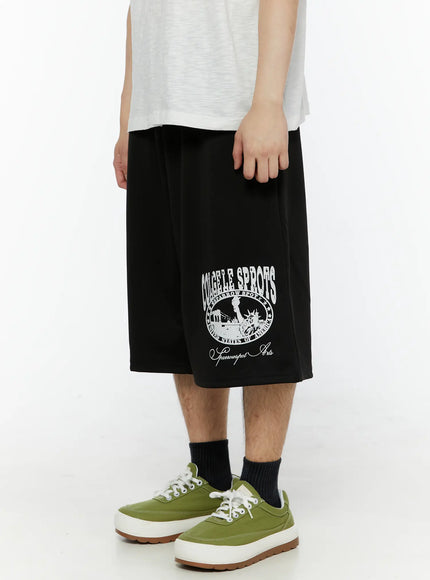 Men's Casual Number Print Shorts (Black) IL509 Black angled side view on model highlighting collegiate Sparrowspot Arts circle logo print detail on right leg, relaxed fit