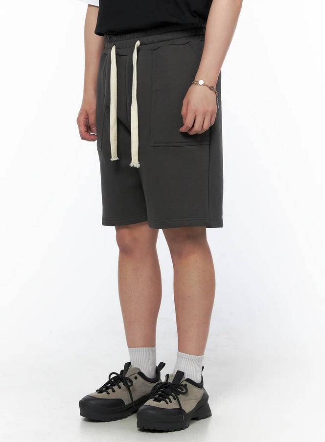 Men's Casual Sweat Shorts (Dark Gray) IL502 Dark Gray side-angle on model showing cream drawstring detail and side pocket, paired with black tee and sneakers