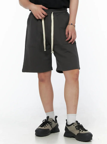 LEWKIN Men's Casual Sweat Shorts (Dark Gray) IL502 Dark Gray close-up front on model size M/L with cream drawstring and patch pockets, styled with black tee and chunky sneakers