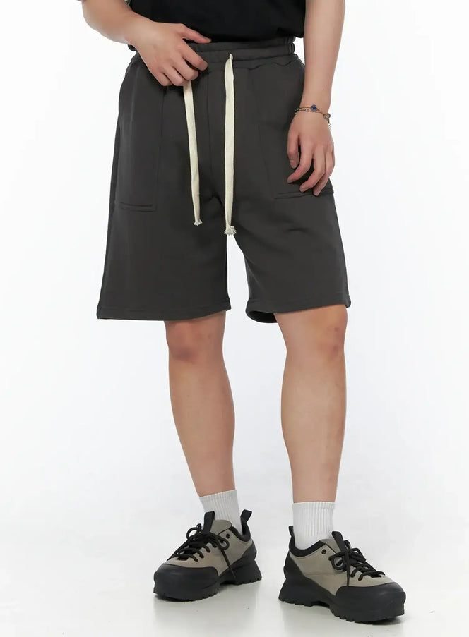 LEWKIN Men's Casual Sweat Shorts (Dark Gray) IL502 Dark Gray close-up front on model size M/L with cream drawstring and patch pockets, styled with black tee and chunky sneakers