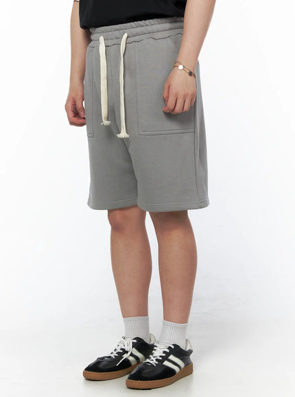 Men's Casual Sweat Shorts (Gray) IL502 gray three-quarter side view on model showing cream drawstring elastic waist and large front patch pocket with fleece texture