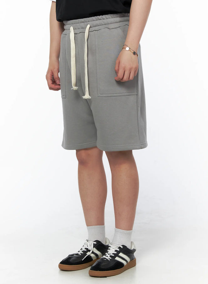 Men's Casual Sweat Shorts (Gray) IL502 gray three-quarter side view on model showing cream drawstring elastic waist and large front patch pocket with fleece texture