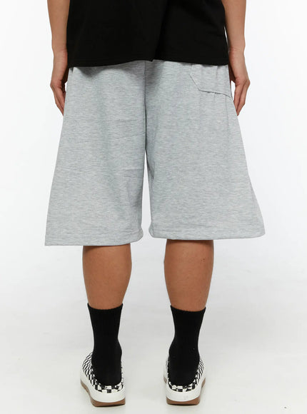 Men's Casual Sweat Shorts IL510 gray back view on male model showing wide A-line hem, back patch pocket, elastic waistband, paired with black tee and checkered sneakers