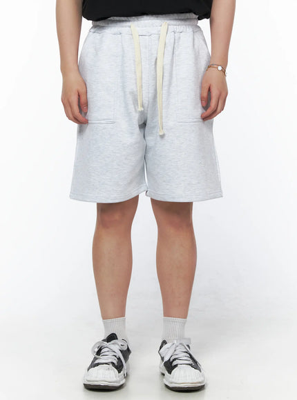LEWKIN Men's Casual Sweat Shorts (Light Gray) IL502 Light Gray front view on model wearing black tee and sneakers, elastic waistband with cream drawstring, patch pockets, fleece fabric