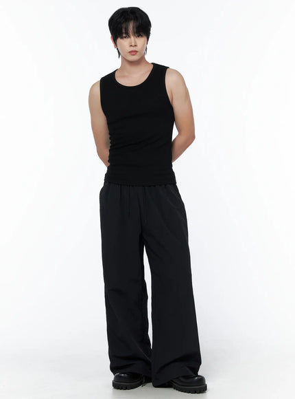 Men's Casual Tank IL502 Black front view on model with hands behind back, paired with wide-leg black drawstring trousers and boots