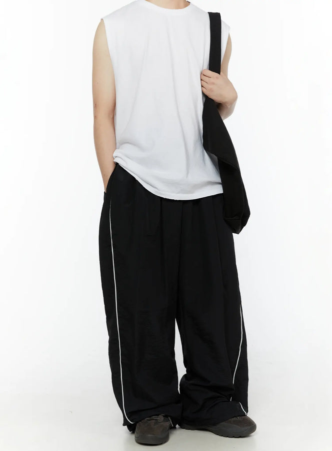 Men's Contrast Piping Nylon Track Pants (Black) IL507 Black front full-body on model styled with white sleeveless top and black tote bag, wide-leg nylon