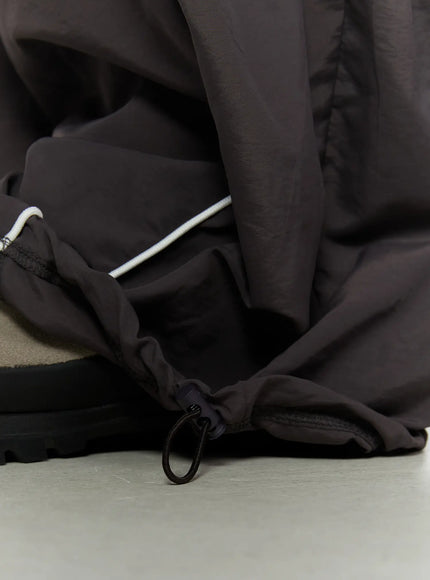 Men's Contrast Piping Nylon Track Pants (Dark Gray) IL507 Dark gray close-up detail of hem drawcord toggle adjuster and white contrast piping at ankle cuff of nylon fabric
