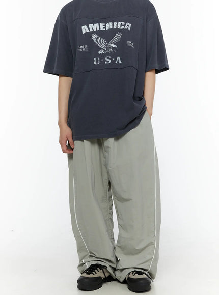 Men's Contrast Piping Nylon Track Pants (Gray) IL507 Gray back three-quarter shot on model styled with America USA graphic tee showing full-length wide leg