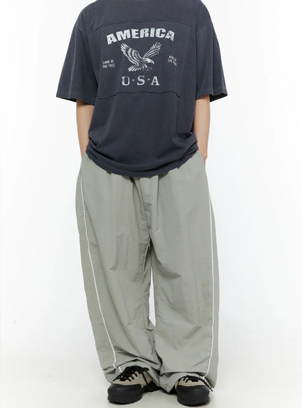 Men's Contrast Piping Nylon Track Pants (Gray) IL507 Gray back full-body shot on model styled with America USA graphic tee showing overall wide-leg silhouette