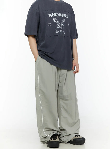 Men's Contrast Piping Nylon Track Pants (Gray) IL507 Gray front three-quarter shot on model with America USA graphic tee hands in pocket showing side piping