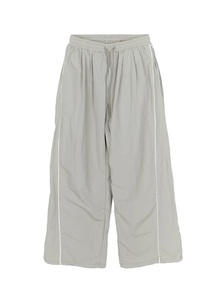 Men's Contrast Piping Nylon Track Pants (Gray) IL507 Gray flat-lay front view showing elastic drawstring waistband wide leg and white contrast piping on nylon fabric