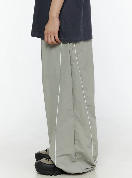 Men's Contrast Piping Nylon Track Pants (Gray) IL507 Gray side shot on model displaying white contrast piping seam and voluminous nylon leg drape