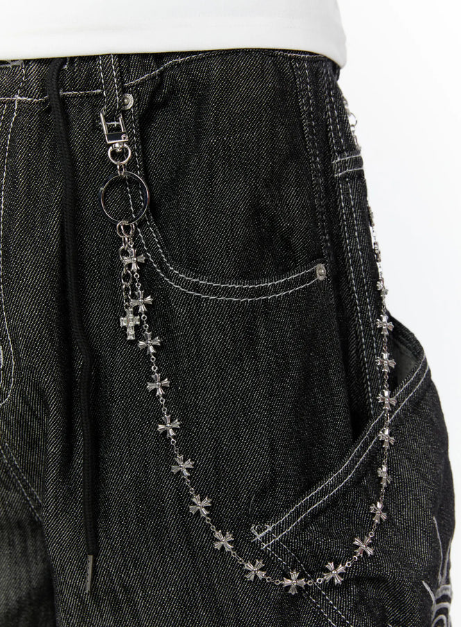 LEWKIN Men's Cross-Link Chain IL509 Silver close-up detail shot clipped to dark denim waistband showing cross charm pendant and draped chain across front pocket