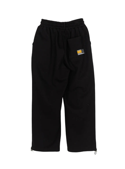 Men's Curved Fit Sweatpants (Black) IL502 black flat-lay back view showing GT 91 UNIVERSAL badge patch side pocket and hem zipper hardware