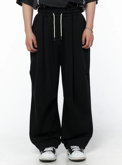 LEWKIN Men's Curved Fit Sweatpants (Black) IL502 black front crop shot on model showing elastic waistband with cream drawstring and wide-leg silhouette