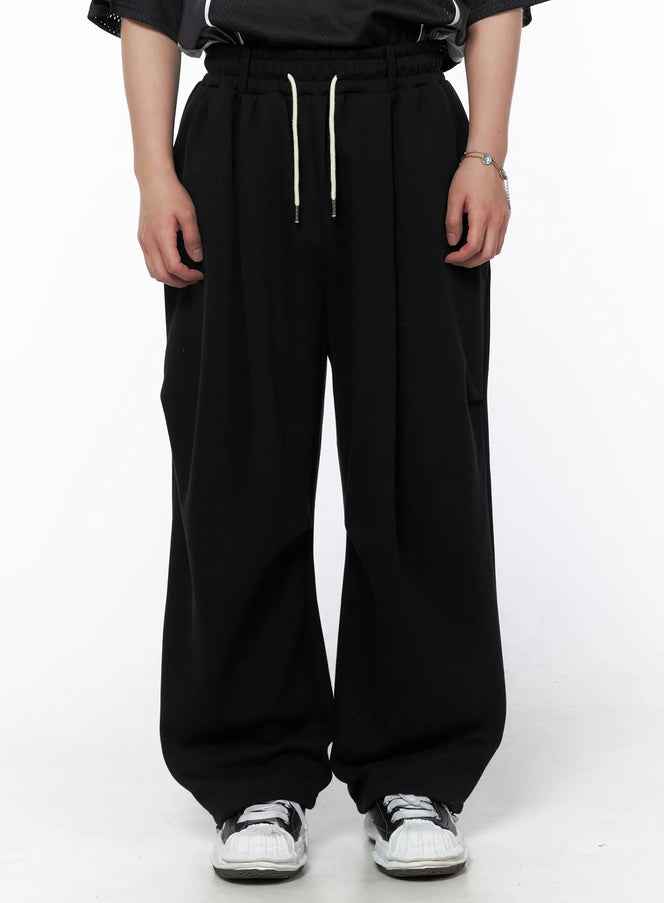LEWKIN Men's Curved Fit Sweatpants (Black) IL502 black front crop shot on model showing elastic waistband with cream drawstring and wide-leg silhouette