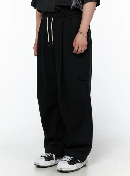 Men's Curved Fit Sweatpants (Black) IL502 black side shot on model highlighting cargo pocket detail cream drawstring waistband and wide-leg cut